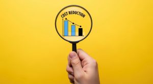 Magnifying Glass Focuses on Cost Reduction Graph on Yellow Background