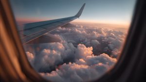 Aerial window view with wing and puffy clouds bathed in warm golden sunset light