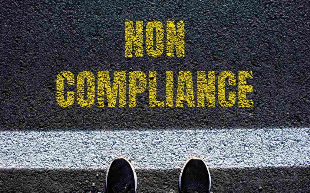 Non compliance message written on asphalt road