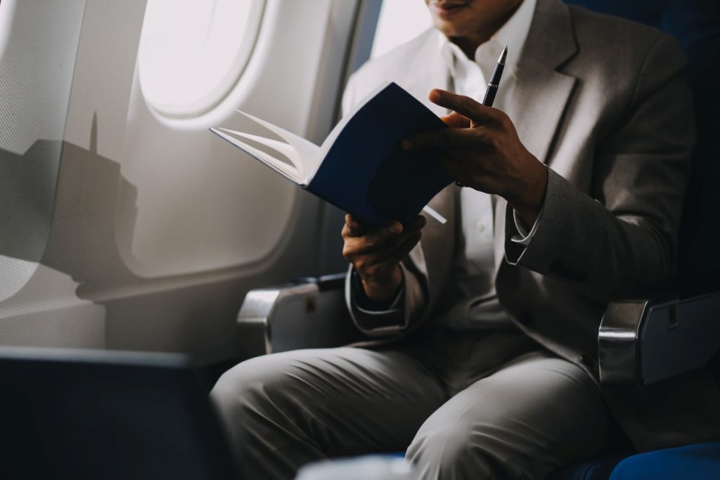 Airplane, travel and portrait of businessman working on laptop computer and smartphone while sitting in airplane