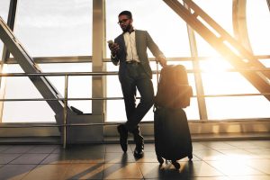 Waiting for Flight. Businessman with Baggage Standing in Airport Terminal