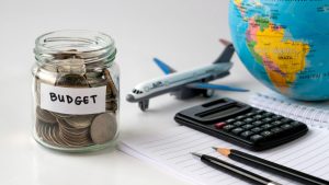 Travel budget jar with coins, globe and airplane for holiday savings