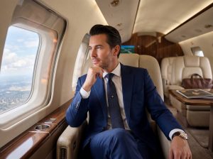 Businessman in blue suit gazing from window of luxurious corporate jet