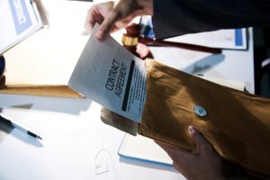 A person is holding a piece of paper with a contract agreement