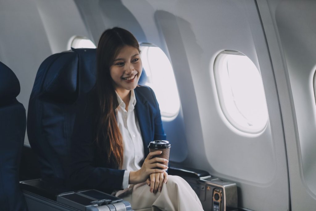 tourist traveling alone on a plane is drinking hot coffee and looking out the window