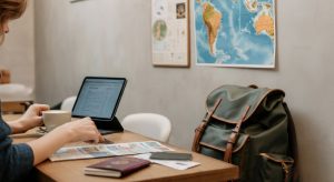 person planning travels with laptop, map, coffee, and backpack