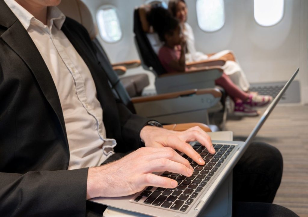 Business man using laptop in airplane during flight