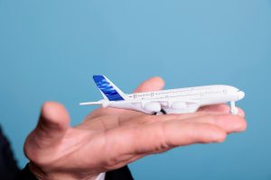 Close up of aviator holding plane toy in hands, playing with commercial passenger jet model