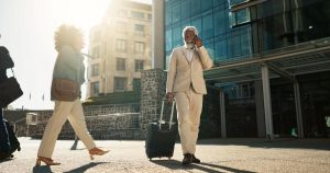 Business man, phone call and suitcase in city, street or conversation for booking, travel or transportation