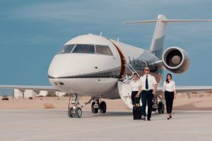 Business pilot and flight crew walking confidently from private jet on airport tarmac for corporate travel