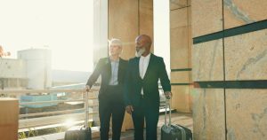 Team, business people and travel with luggage in city for journey, international trip or flight at airport