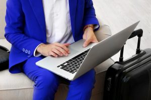 Business man with suitcase and laptop sitting on sofa in hall