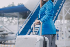Young asian woman in international airport, using mobile smartphone and checking flight at the flight information board