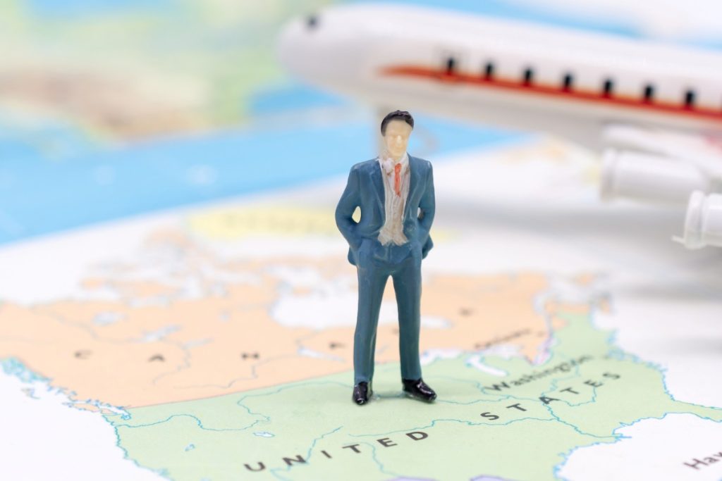 Miniature people, businessman standing on map American